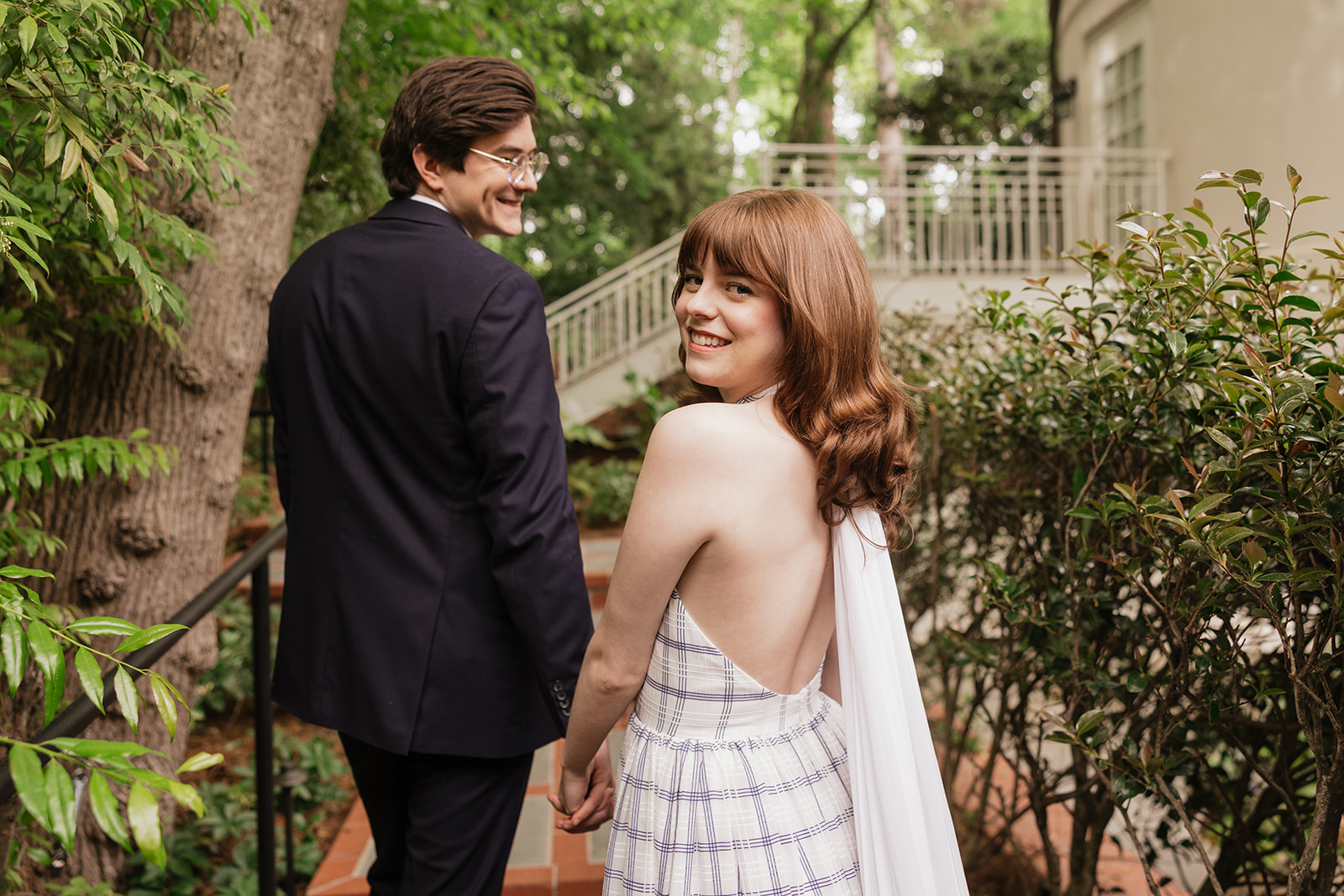 Elizabeth and Nicholas holding hands and looking back on a garden path.