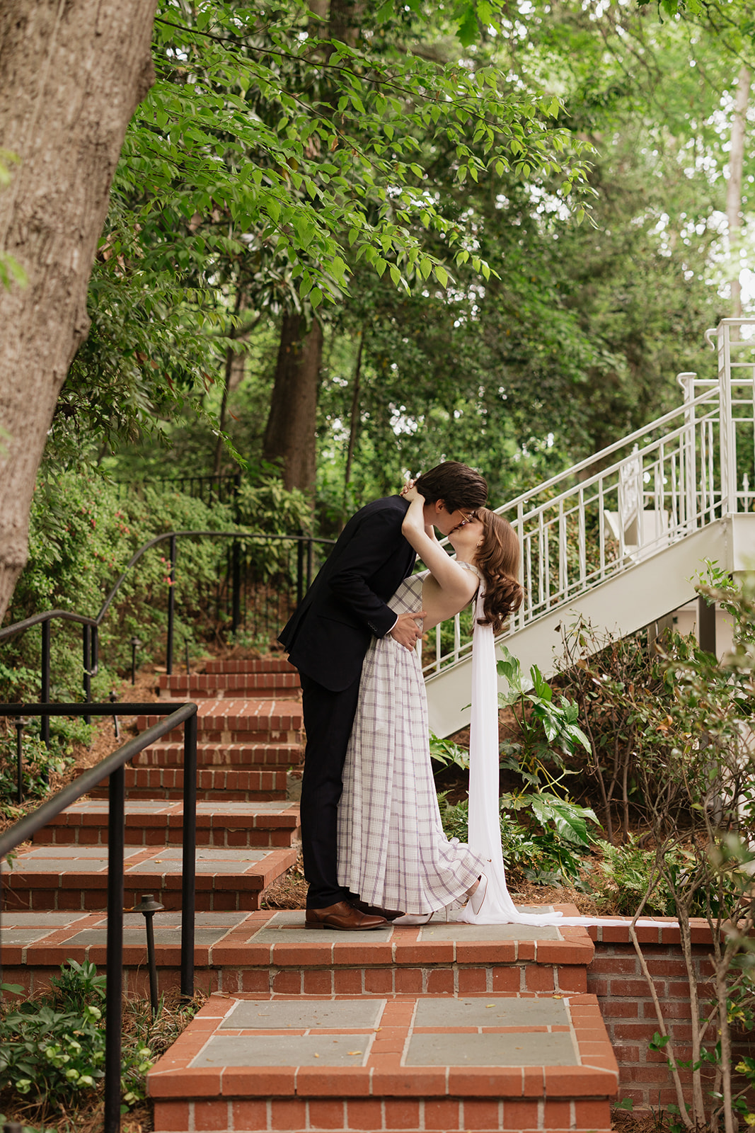 Elizabeth and Nicholas kissing on brick garden steps.